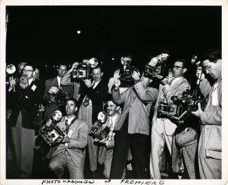 Black and white photograph of a group of photographers with their cameras at a premiere